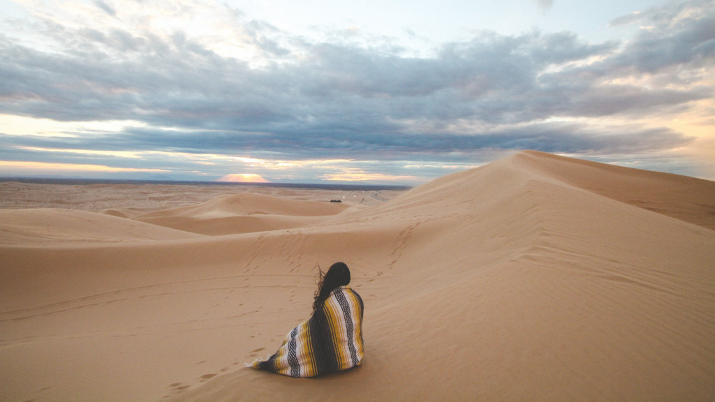 woman alone on a sand dune looking at the horizon