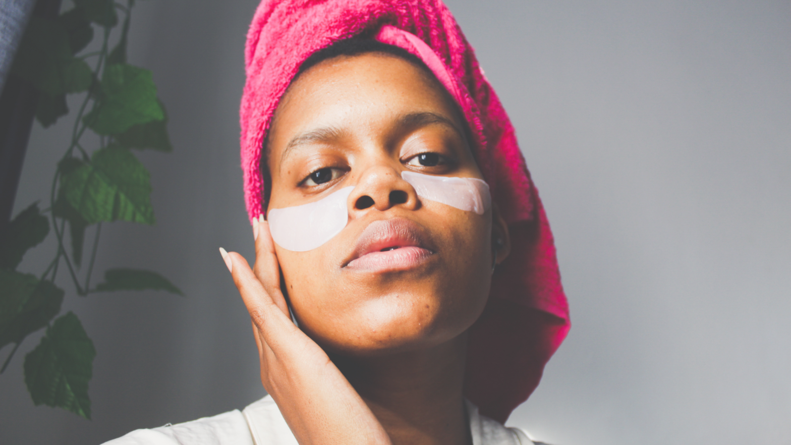 woman wearing a pink towel headwrap with undereye mask for skincare